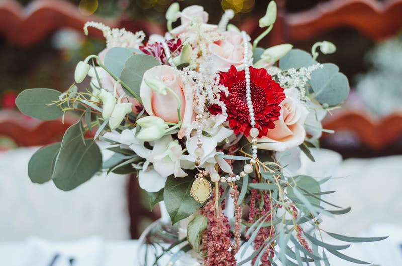 bridal bouquet with eucalyptus, blush roses, white and red flowers, and jewelry