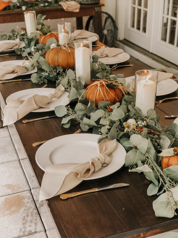 modern fall tablescape with greenery and candles in hurricane vases