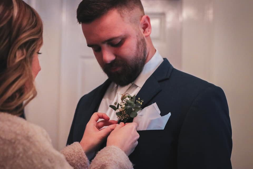 Mother of the groom pinning a boutonniere on the groom's suit.