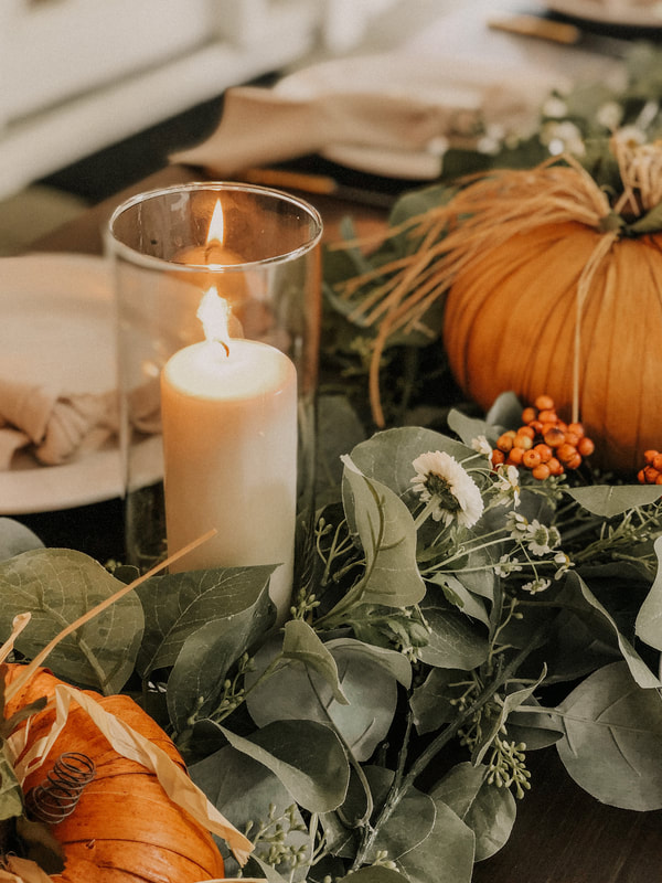 eucalyptus greenery runner with candles in vases, husk pumpkins, and white flowers
