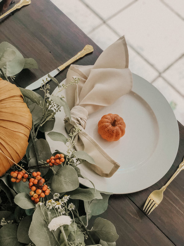 neutral fall place setting with berries and white flowers in centerpiece greenery