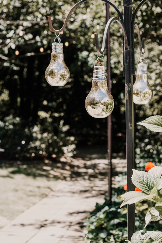 light bulbs hanging from shepherd hooks in outdoor wedding venue