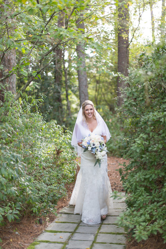 bride v-neck neckline dress holding white and light blue bouquet in gardens