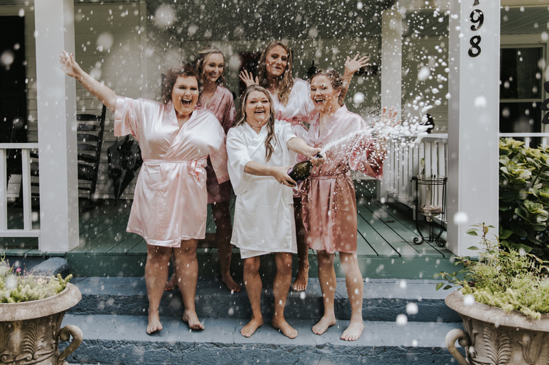 bride and bridesmaids in silk robes popping champagne
