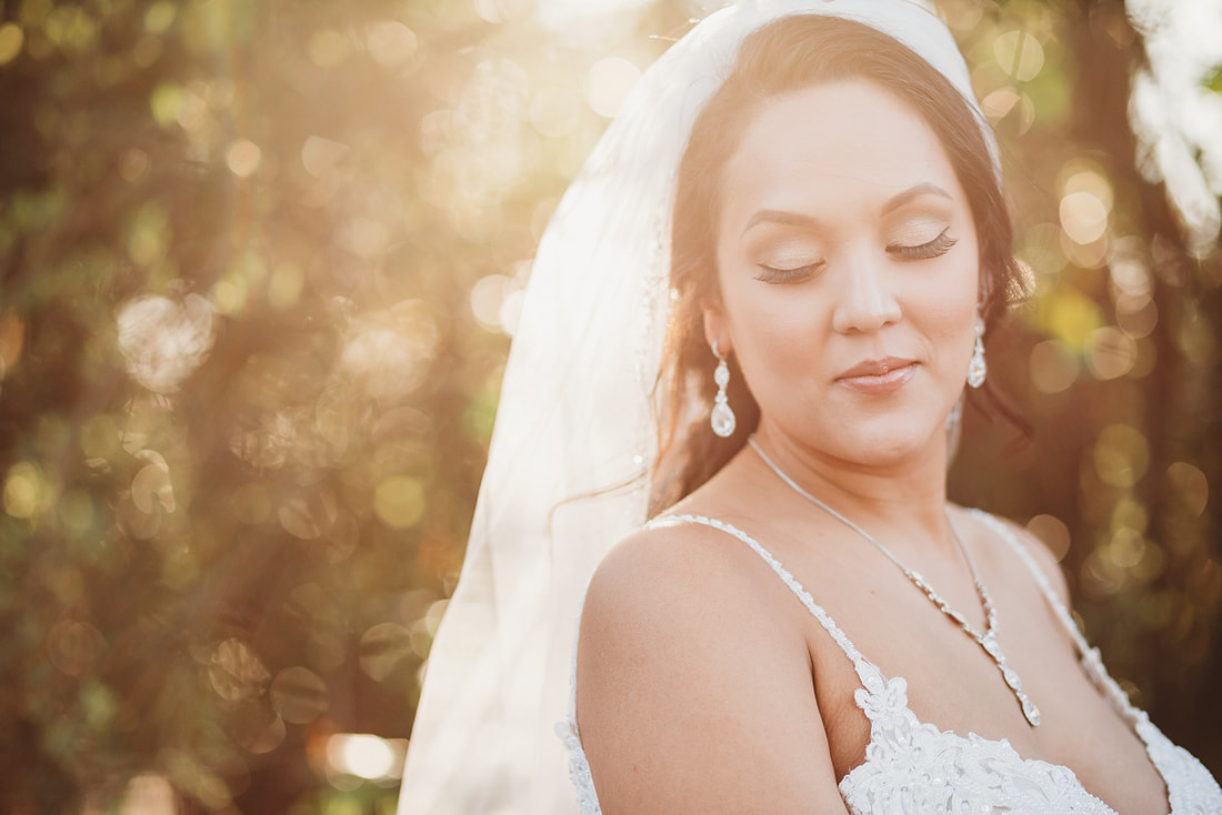 bride in lace dress with diamond jewelry and sun shining behind her