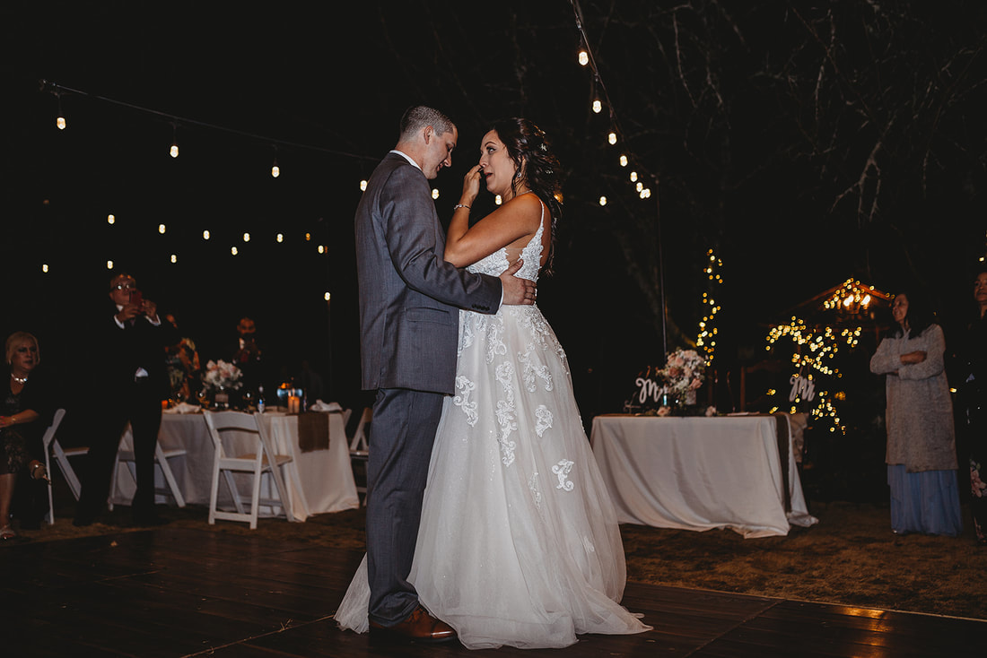 bride and groom sharing first dance under the stars and string lights