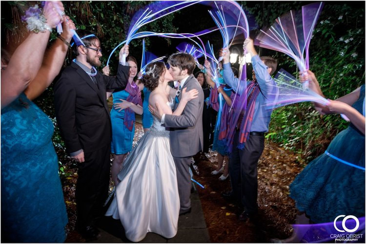 bride and groom kissing as guests wave blue and purple glow sticks