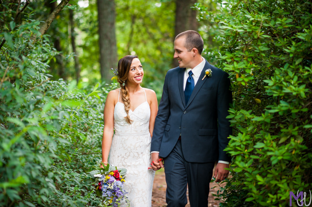 bride and groom holding hands along garden venue path