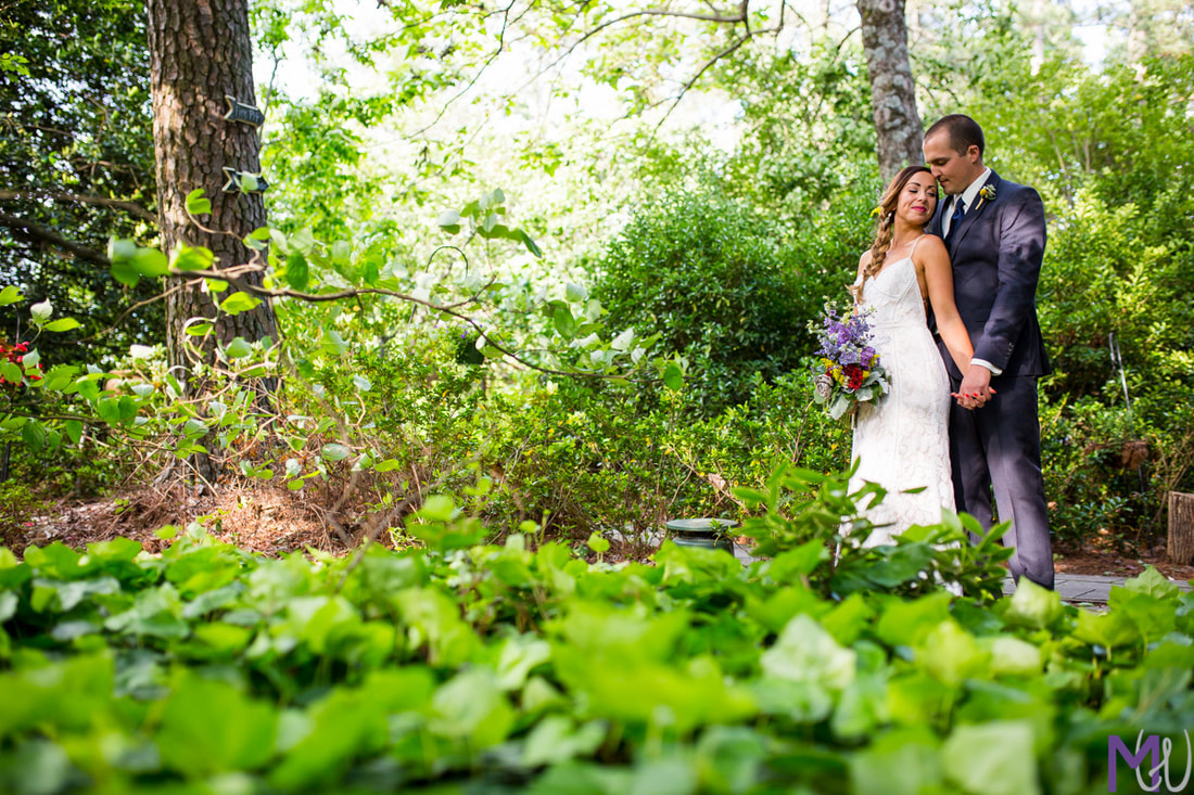 bride and groom pose around lush plants and foliage