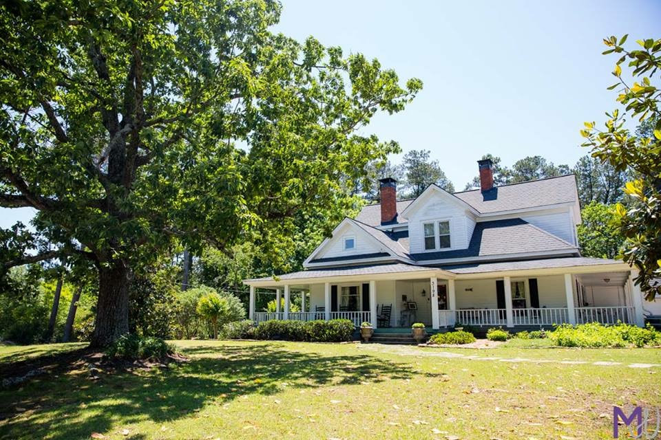 white farmhouse with large oak tree