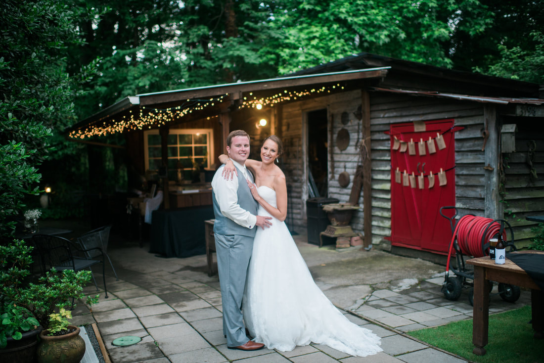 Bride and groom hugging by Four Oaks' smokehouse