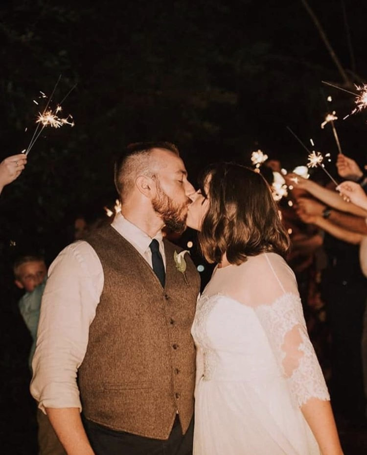 newlyweds kissing during sparklers grand exit at summer wedding