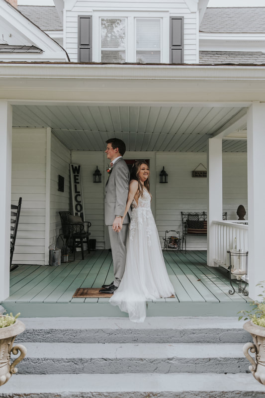 bride and groom standing back to back on farmhouse porch