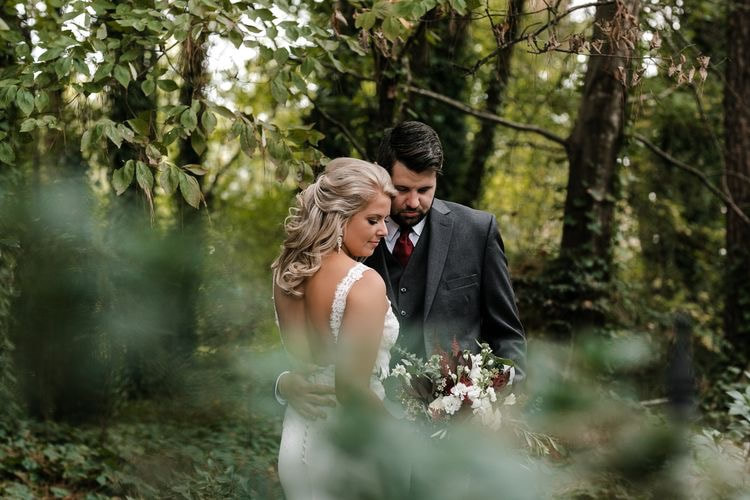 Taylor and Clay standing under the trees in Four Oaks' gardens during their October wedding.
