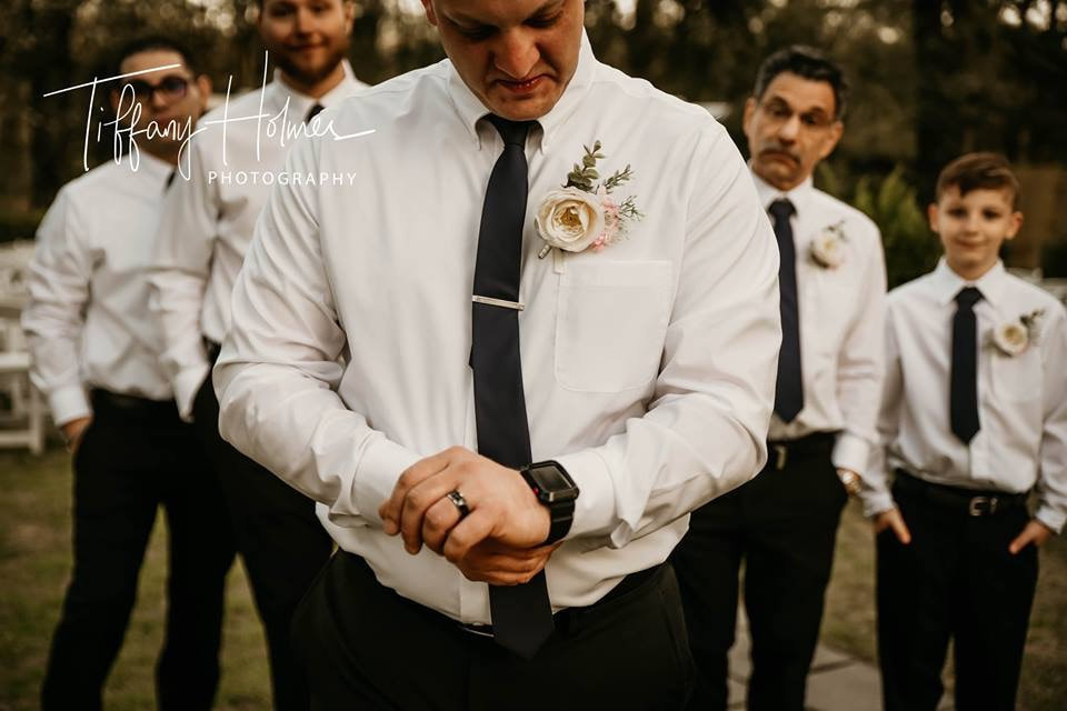 Groom fixing cuff with groomsmen in background