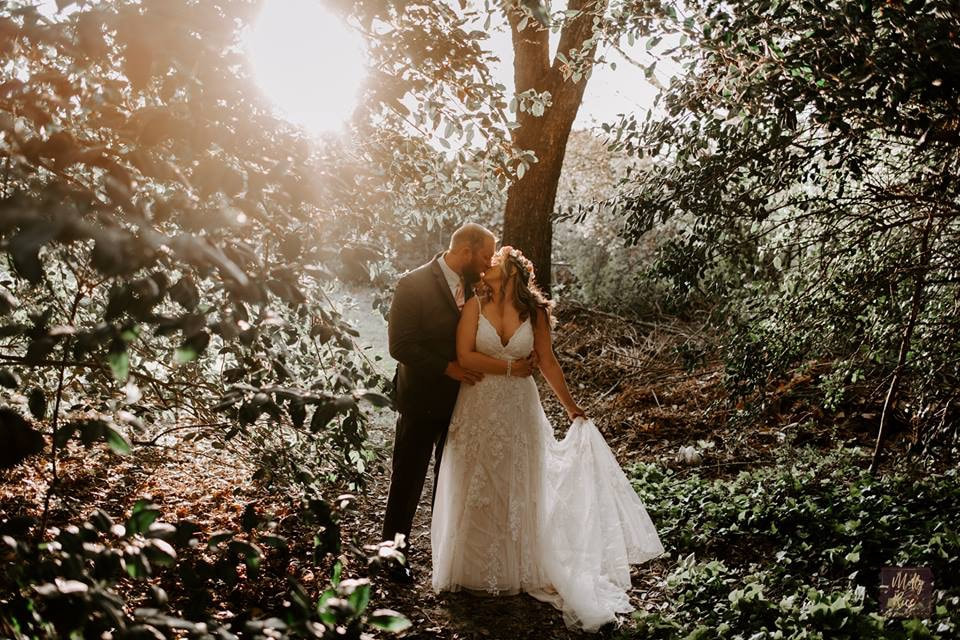 bride and groom sharing a kiss under trees and sunlight