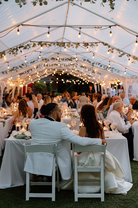 bride and groom sitting at head table of tented reception