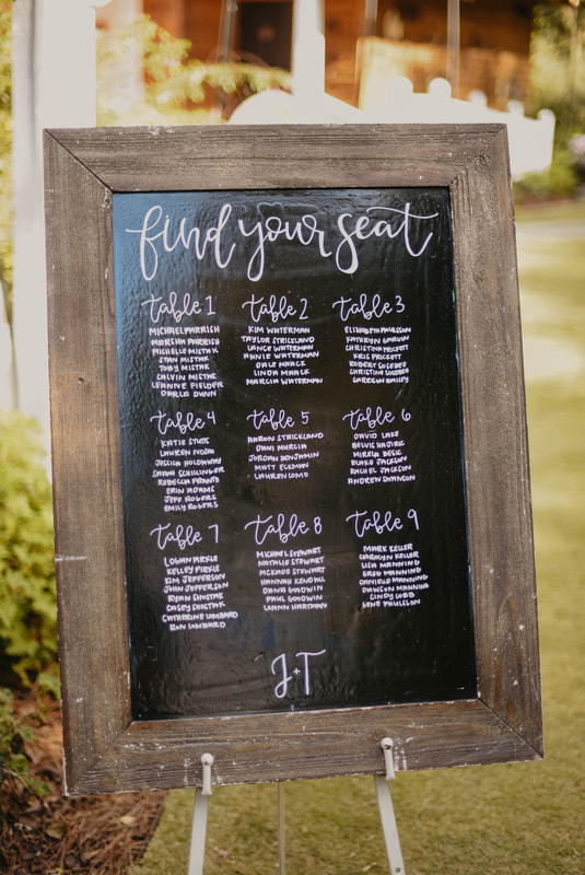seating chart written on large brown chalkboard sign