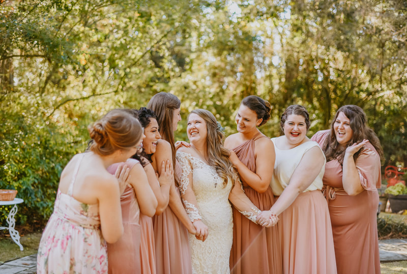 bride posing with bridesmaids in mismatched blush dresses