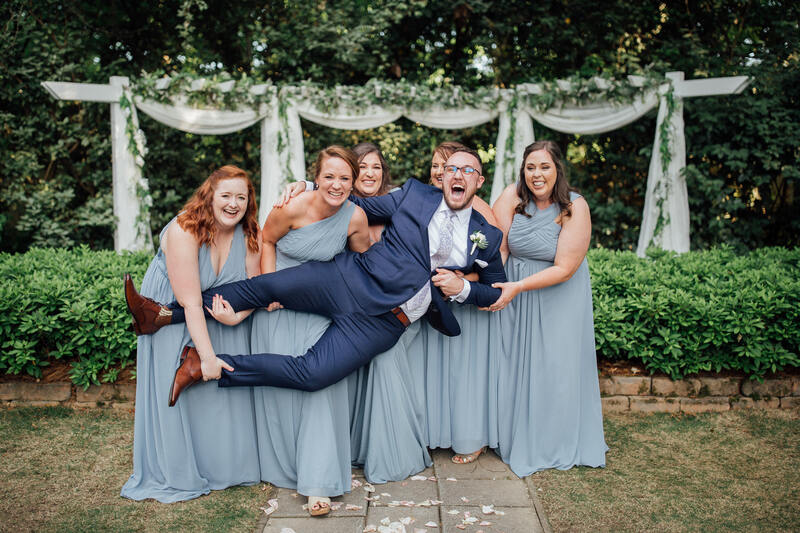 bridesmaids holding up groom by altar
