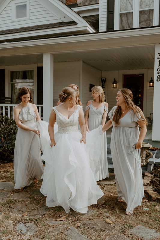 bridesmaids helping bride down steps