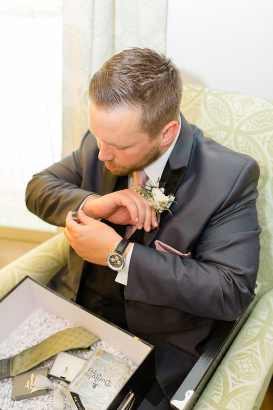 groom putting on cufflinks in farmhouse groom's room