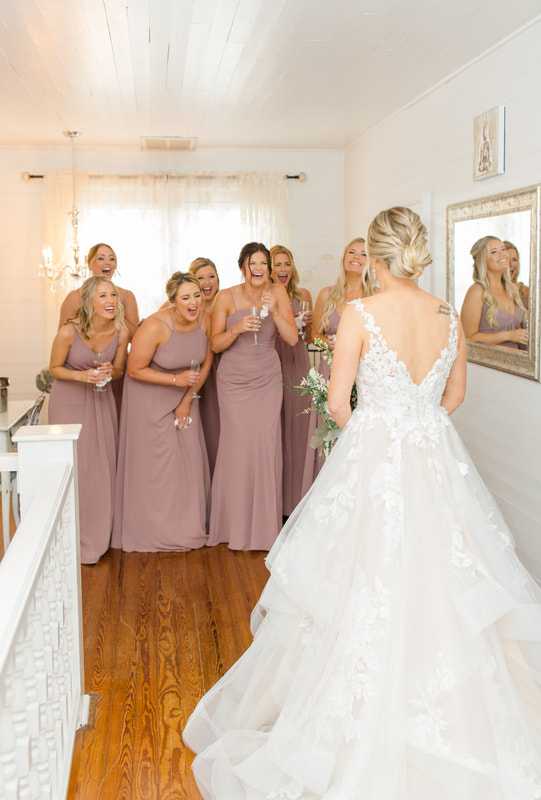 bridesmaids in mauve dresses reacting to bride's reveal