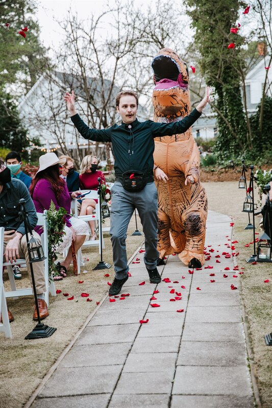 flower man and ring bearer in inflatable dinosaur costume