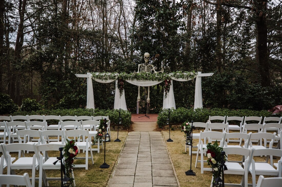 moody outdoor ceremony with 12-foot skeleton behind altar