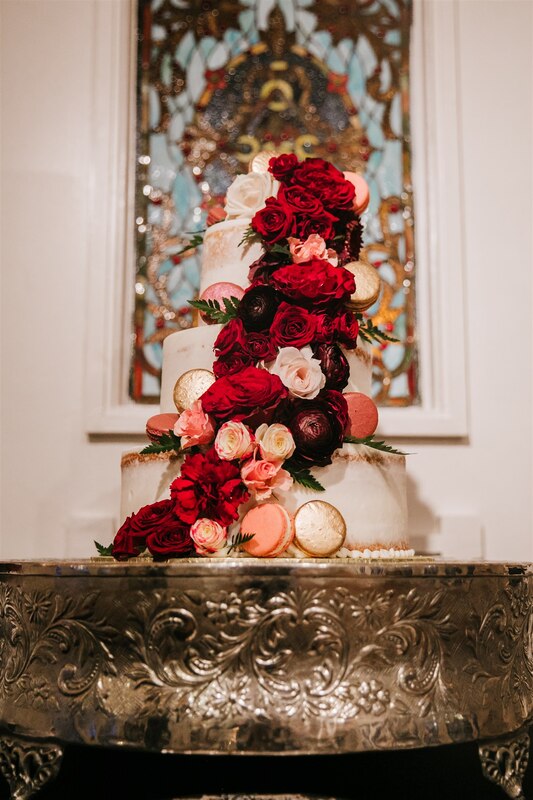 3-tier wedding cake with burgundy, blush, and gold macarons and flowers