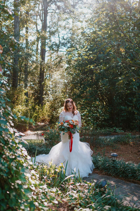 october bride posing in garden wedding with sunlight shining behind