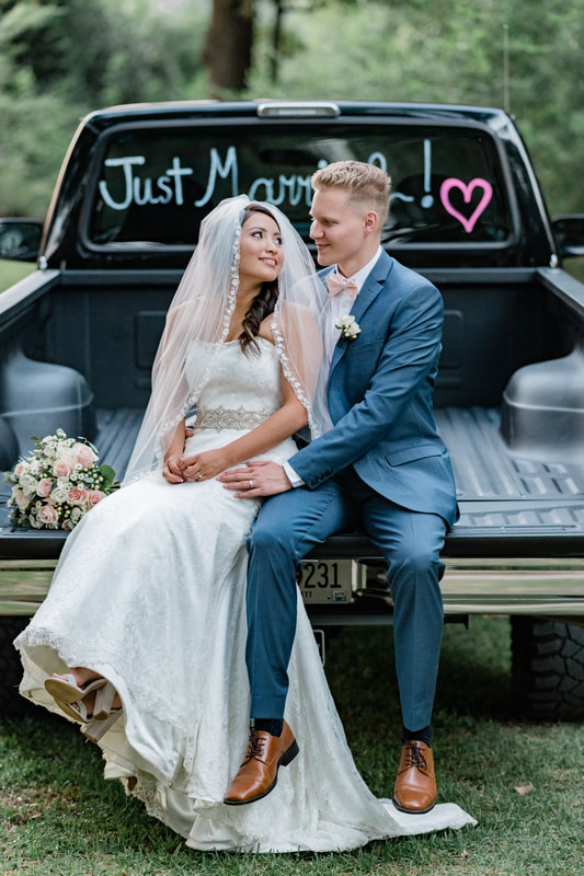 couple sitting on truck bed with 'just married' on window