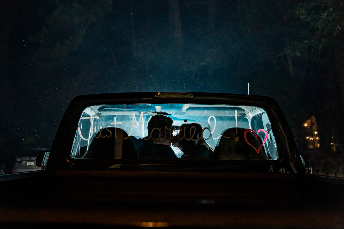 bride and groom kissing in truck with light shining