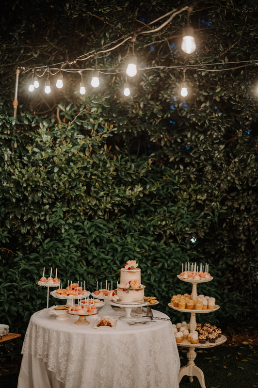 cake and dessert display at garden wedding venue in front of holly berry bush