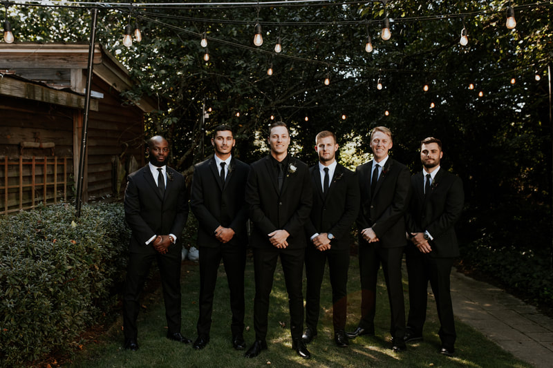 groomsmen in black suits with groom in all-black