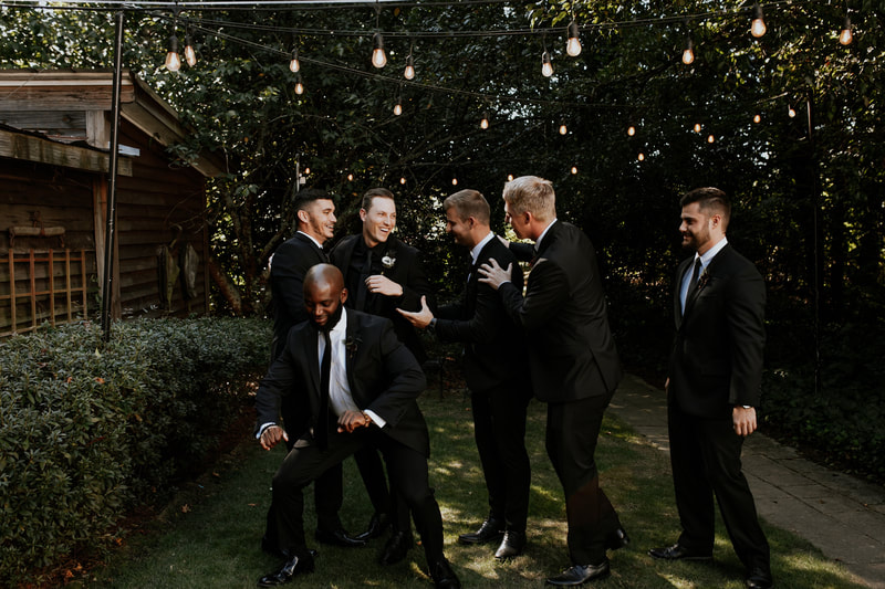 groomsmen and groom laughing in Four Oaks' gardens