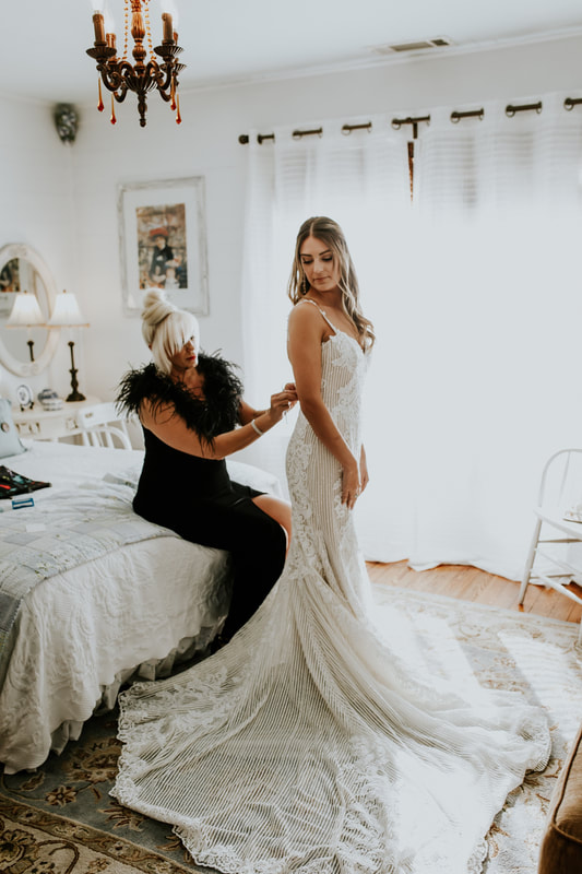 mother buttoning bride's dress in bridal bedroom