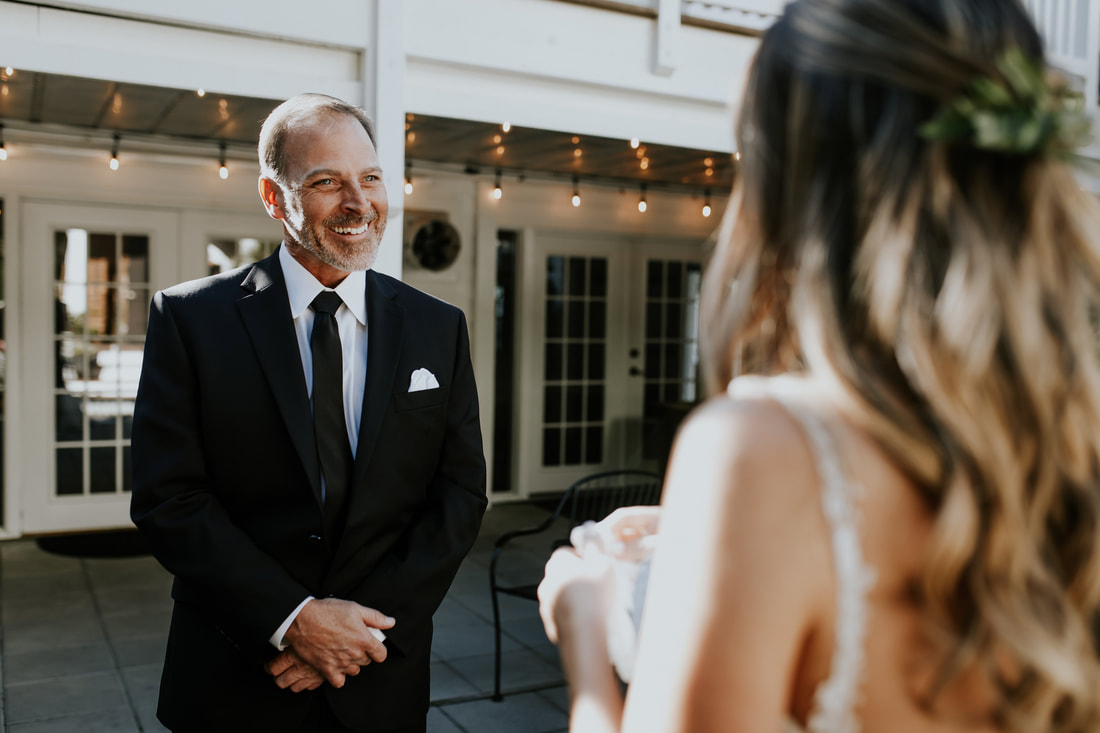 father smiling at bride during first look