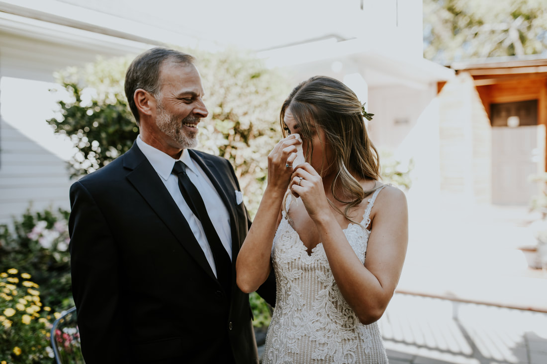bride wiping away tears after first look with dad