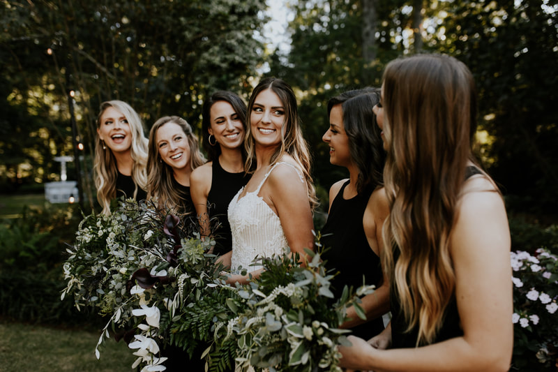 boho chic bride standing with bridesmaids in black dresses