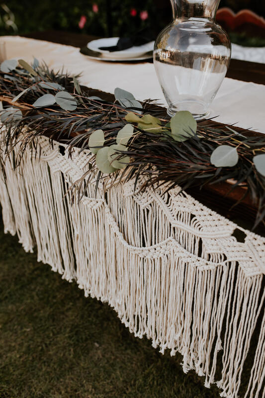 macramé on head table with greenery and vase