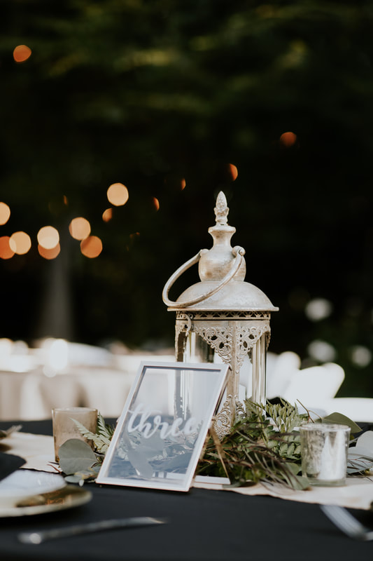 gold wedding centerpiece with antique lantern, greenery and glass table number