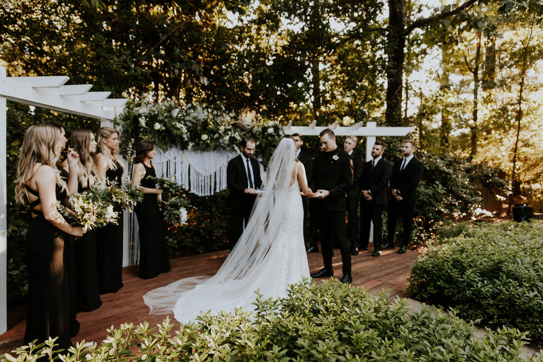 modern boho garden ceremony with black dressed bridal party