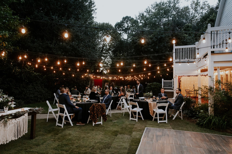 guests sitting at reception tables under bistro lights
