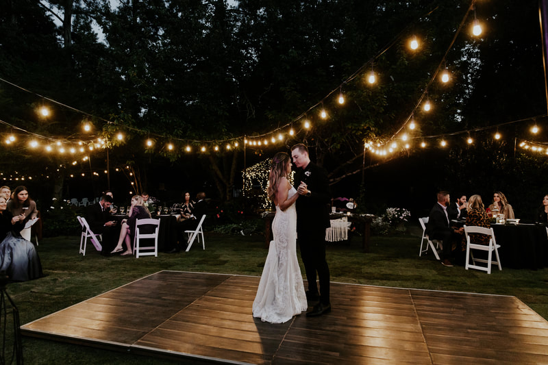 newlyweds dancing on outdoor dance floor under string lights