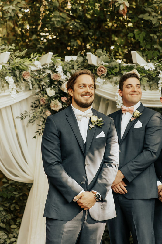 groom in charcoal suit smiling at altar