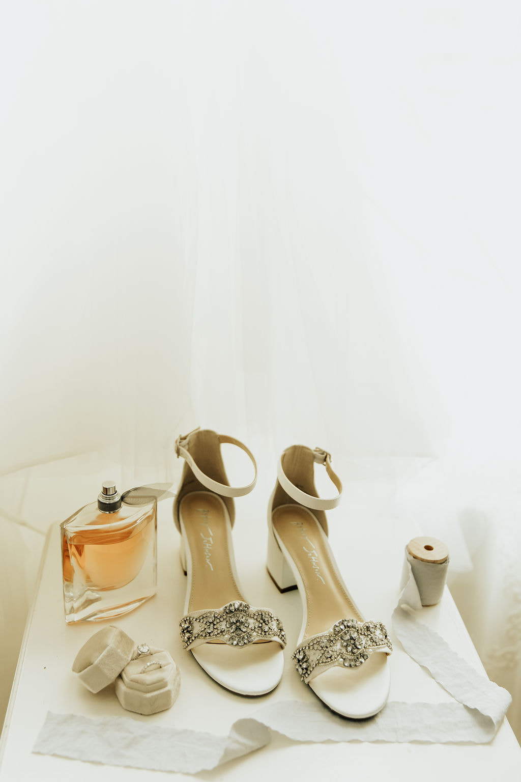 bride's accessories on white side table with sage green ribbon