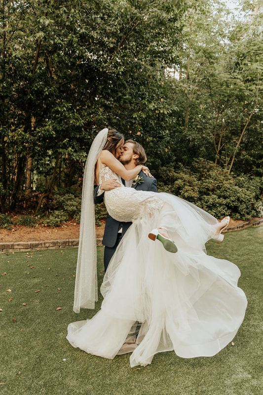 groom holding bride in arms and kissing