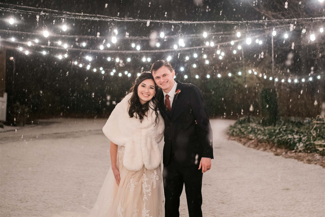couple standing in garden venue while it's snowing