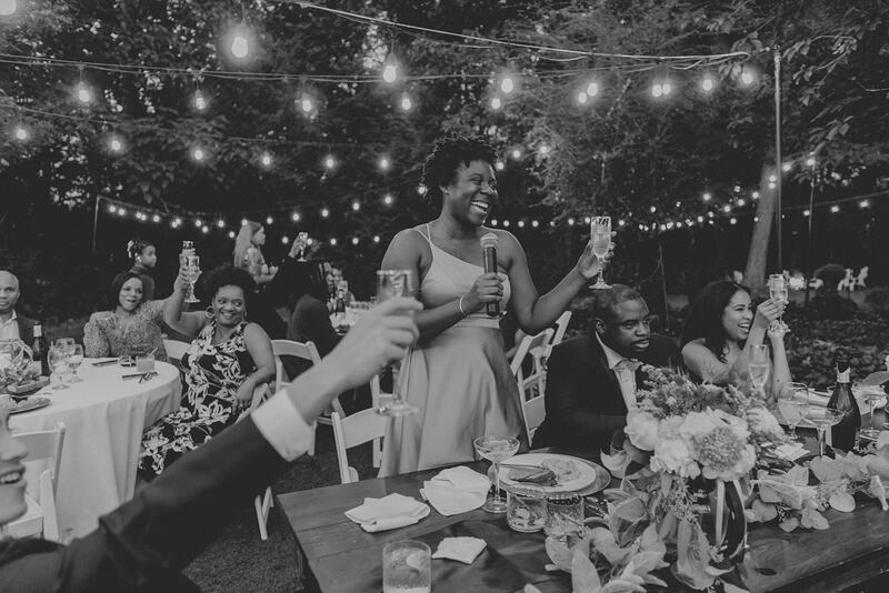 black and white photo of MOH wedding toast at garden venue